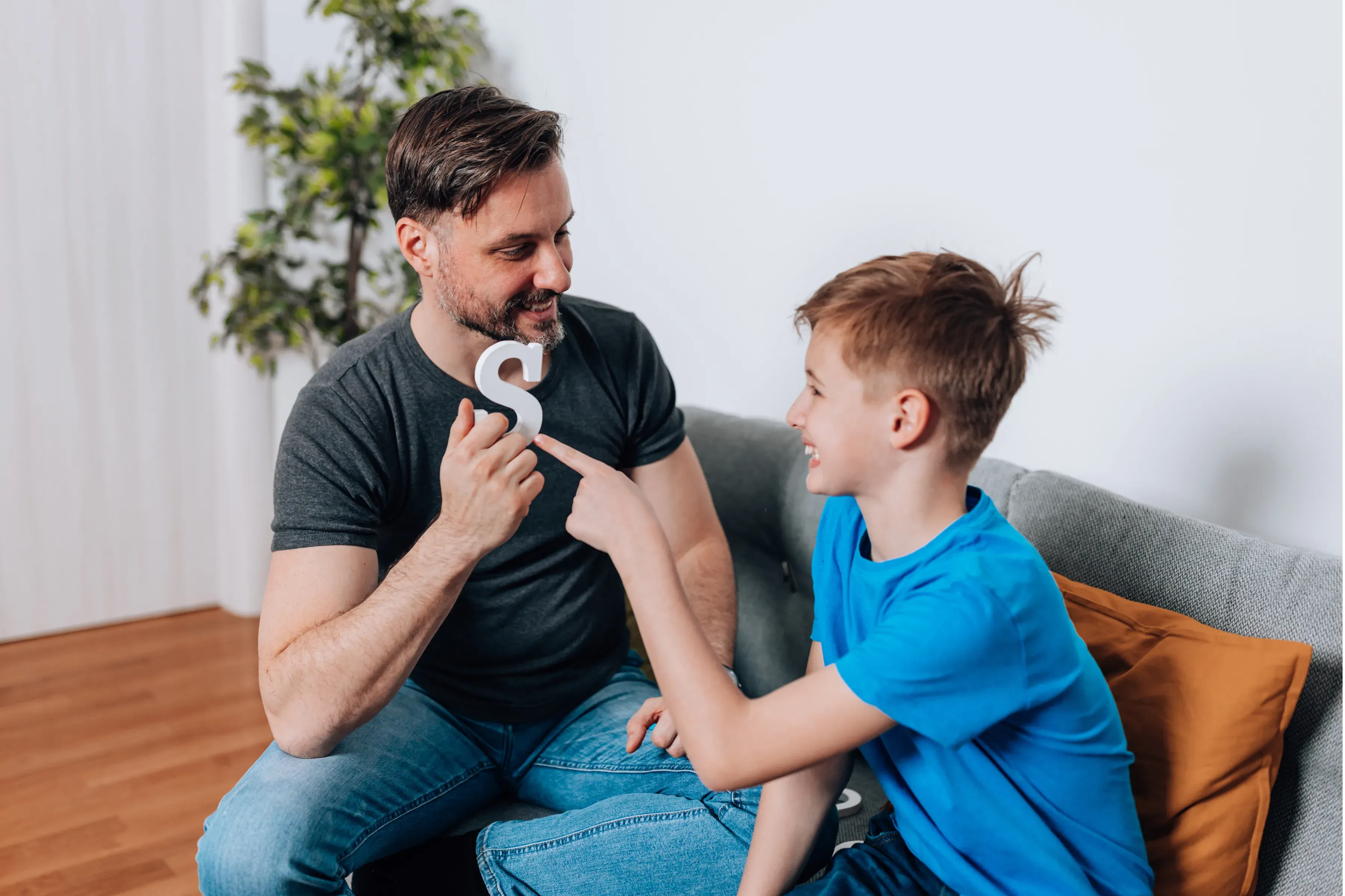 A clinician and young client practice a speech sound using a letter prompt.