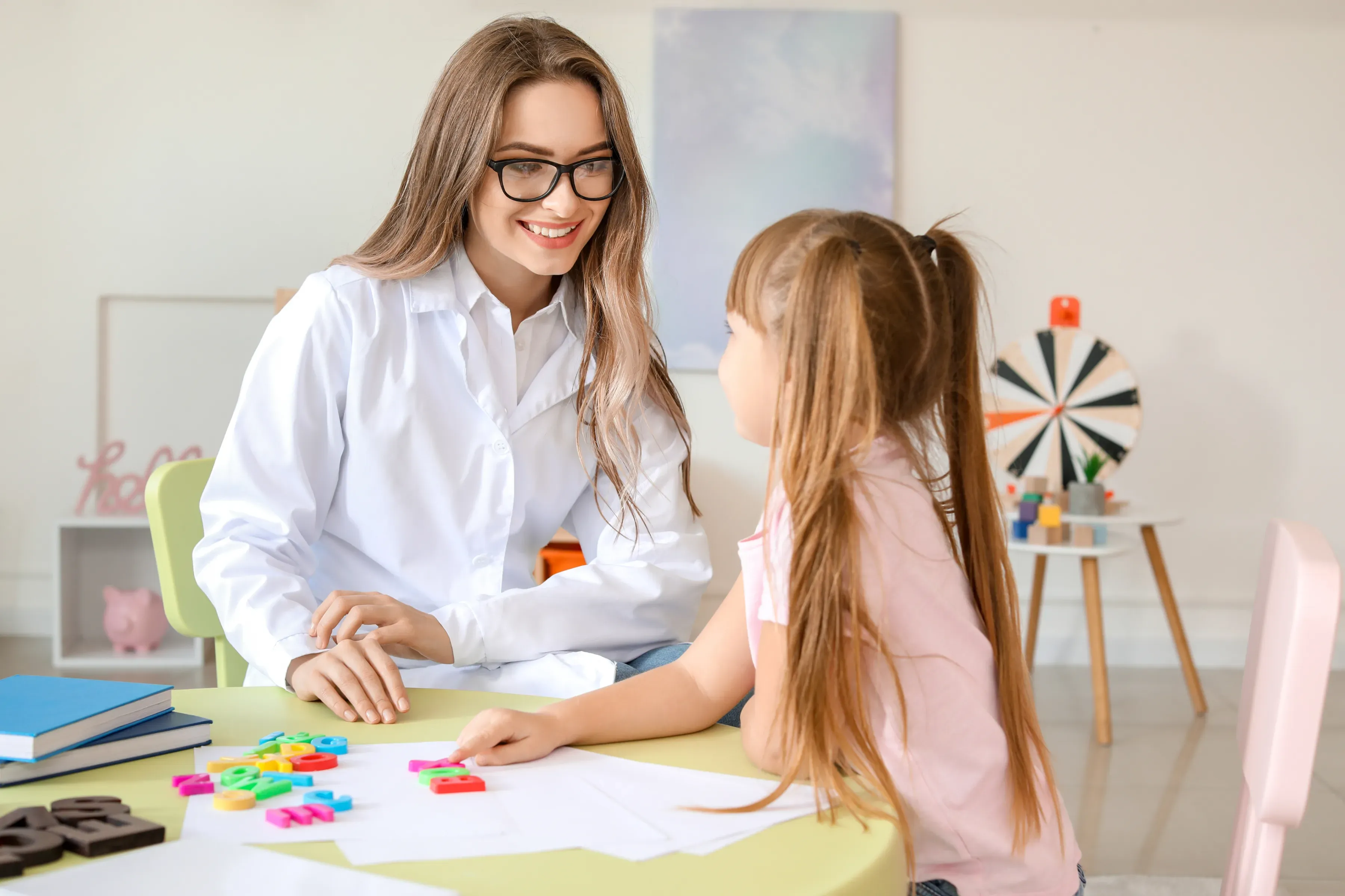 A clinician working with a young client at a table.