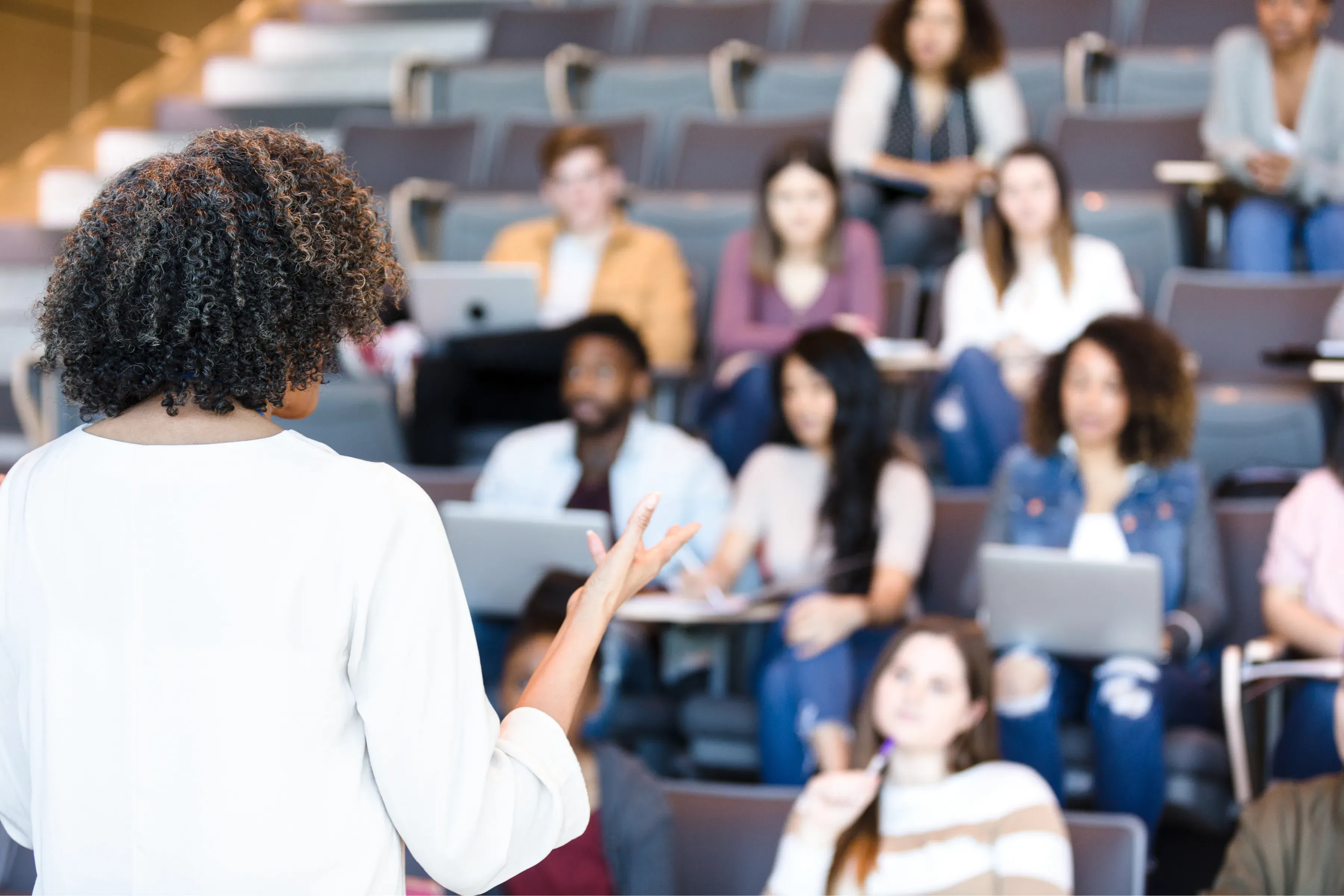 An educator teaching students in a university lecture hall.