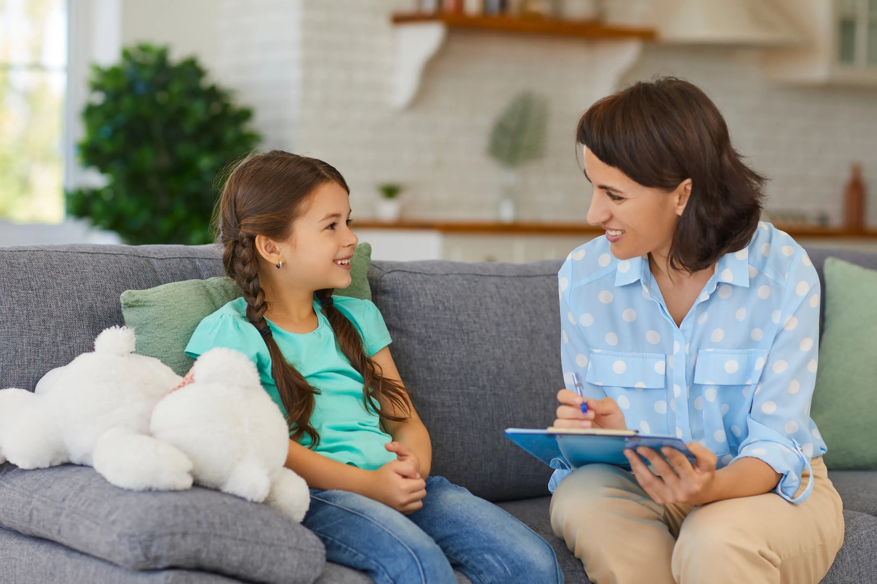 A researcher speaking with a young participant while taking notes.